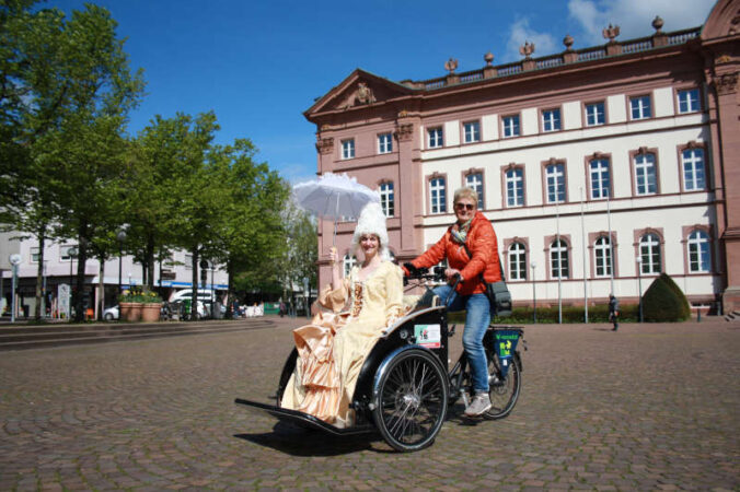 Die Herzogin alias Katrin Stegner und die Fahrerin Elisabeth Lelle mit der Rikscha des Projekt „Radeln im Alter“ der Gruppe „Zweibrücken vernetzt“. (Foto: Stadt Zweibrücken)