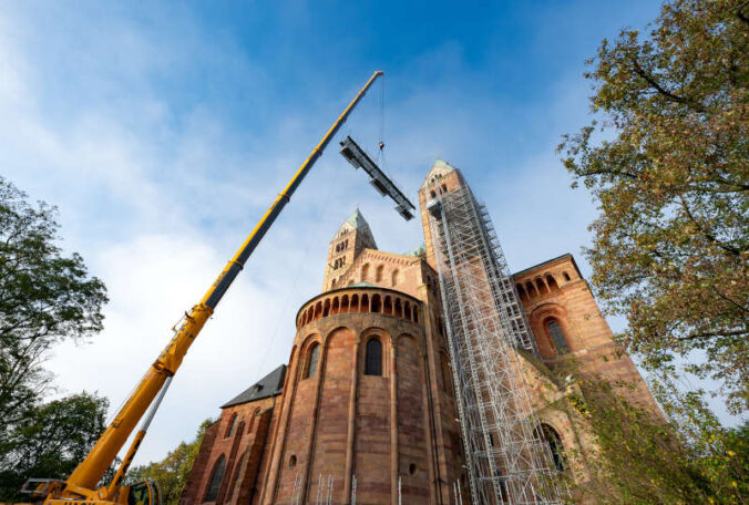 Ein Teleskopkran transportiert vormontierte Gerüstteile zum Bestimmungsort am Südostturm des Doms. (Quelle: Domkapitel Speyer, Foto: Klaus Landry)