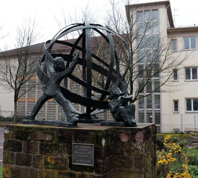 Bereits anlässlich des 25-jährigen Jubiläums der Realschule wurde ein Kunst-am-Bau-Wettbewerb ausgelobt. Er setzte den Schlusspunkt um die damalige Umbauphase am Nagelschmiedsberg. Die Bronzeplastik „Weltkugel mit zwei Schülern“ stammt von Herbert Lorenz und wurde im Oktober 1993 eingeweiht. (Foto: Stadtverwaltung Pirmasens / Maximilian Zwick)